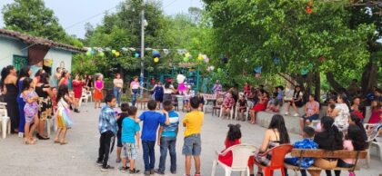 Residents of Plazuelas in a circle at an outdoor celebration with a piñata