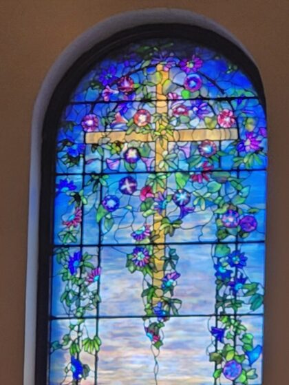Stained glass window depicting a cross wrapped in flowers